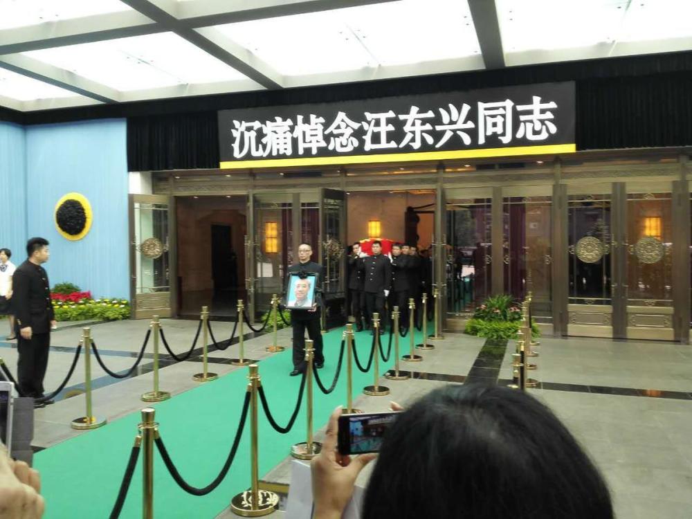 告别仪式结束后，汪东兴之子汪振凯手捧父亲遗像从礼堂走出。
