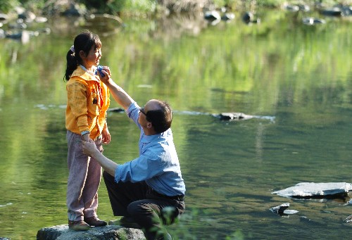 5月23日，教师汪来九在深山的小溪旁为学生擦脸。