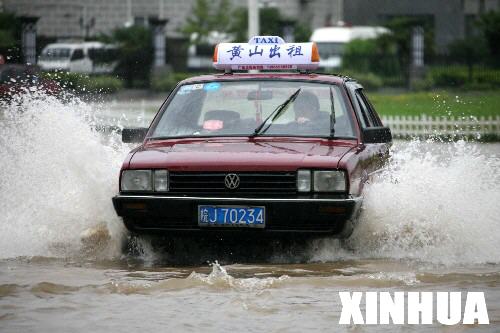 5月9日，在黄山市街头，一辆出租车在积水中行驶。
