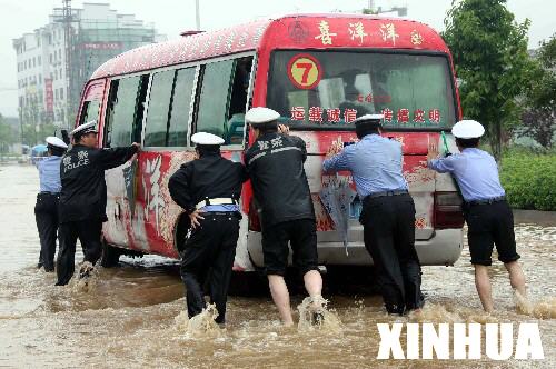 5月9日，在黄山市街头积水中，几名警察推着熄火的公交车前行。