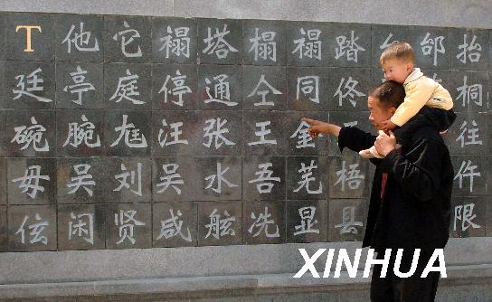 4月19日，一位肩扛孩子的老人在观看中华姓氏墙。当日，位于河南新郑市黄帝故里门前的百姓广场正式对外开放