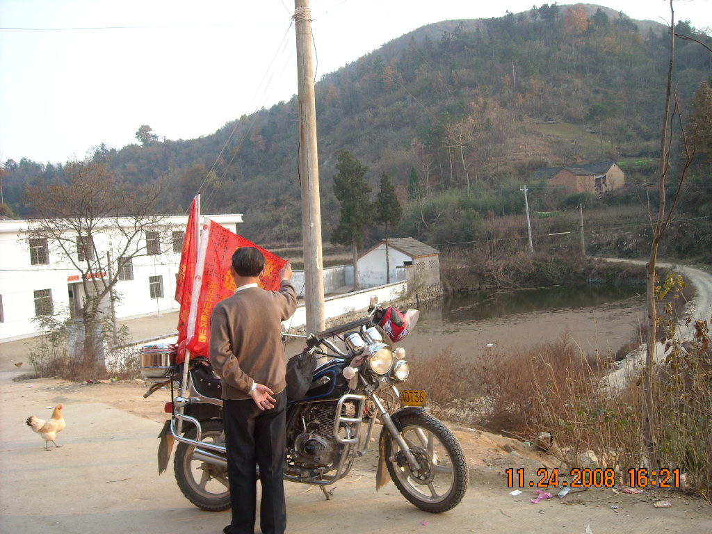 汪家冲汪氏后裔正看锦旗上签名，老祠前面月牙塘