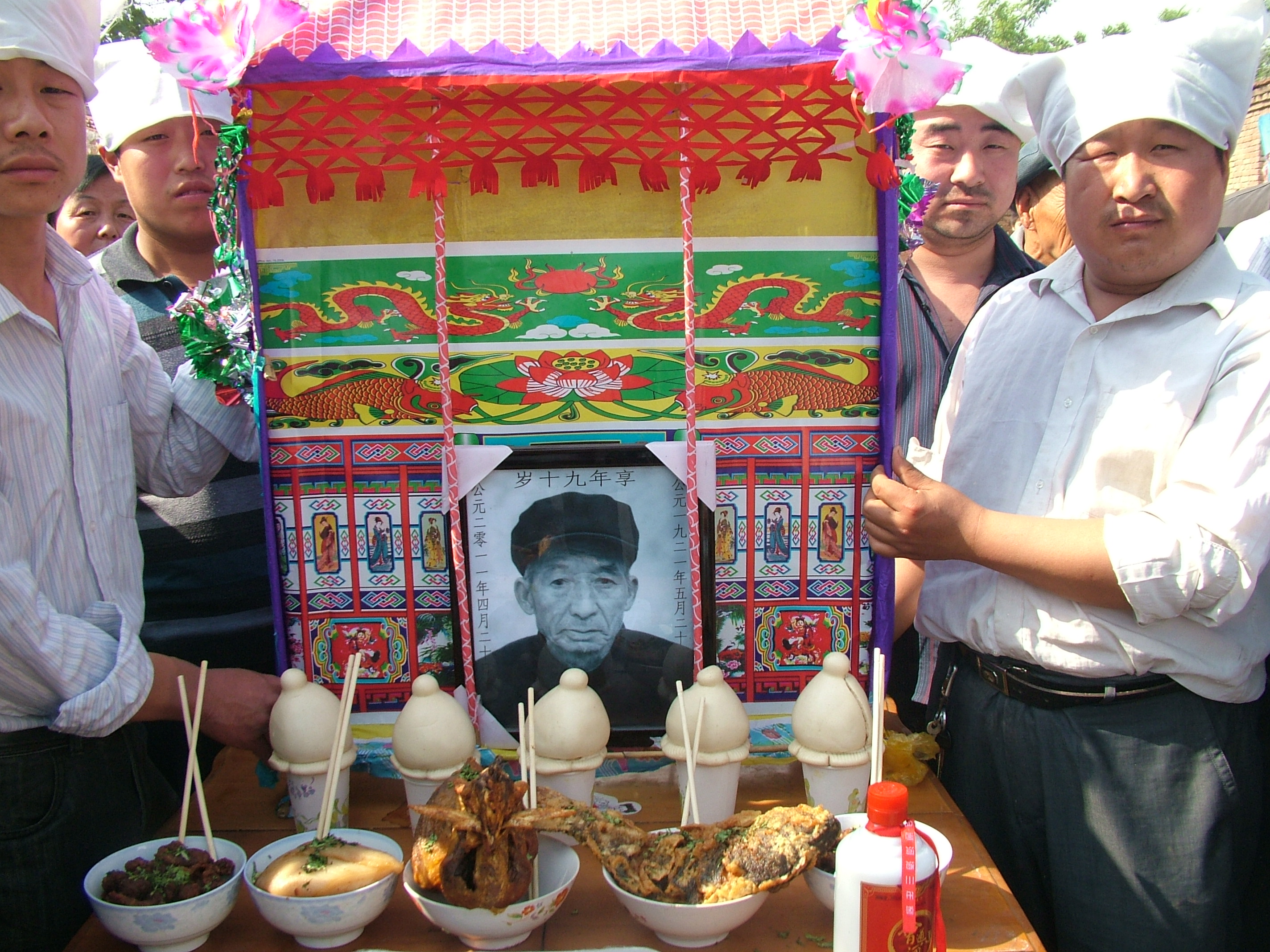 因为有点风，老八爷的遗照被后辈们护佑着。